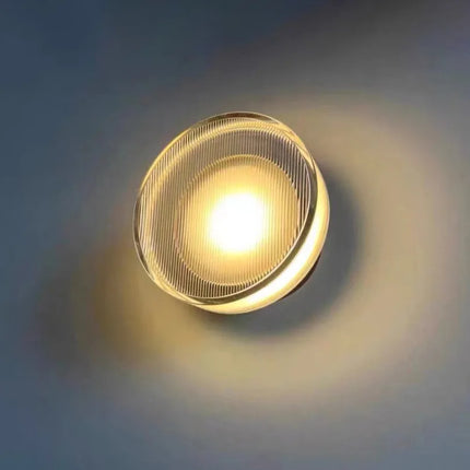 Applique murale ronde en acrylique rainuré allumée diffusant une lumière chaude sur le mur