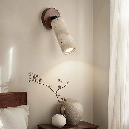 Applique en travertin diffusant une lumière chaude au-dessus d'un vase et d'une branche