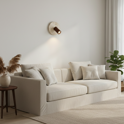 Applique en travertin et bois installée dans un salon minimaliste au-dessus d'un canapé beige