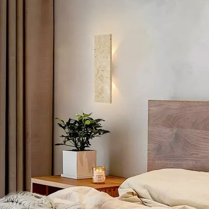 Applique en travertin au-dessus d'une table de chevet dans une chambre au style naturel
