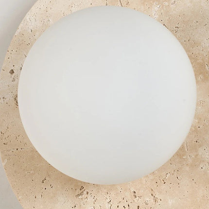 Détail du globe en verre opalin blanc encastré dans le disque de travertin naturel