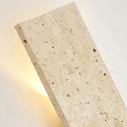Détail de l'applique en travertin montrant le relief de la pierre et le halo lumineux latéral