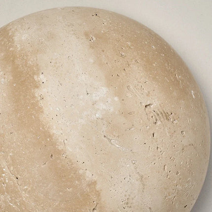 Détail de la texture poreuse et des veines du travertin naturel de l'applique murale ronde