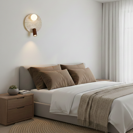 Applique en travertin avec globe en verre allumée au-dessus d'une tête de lit beige