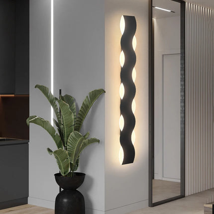 Applique murale en métal noir à silhouette vague installée dans un couloir intérieur épuré