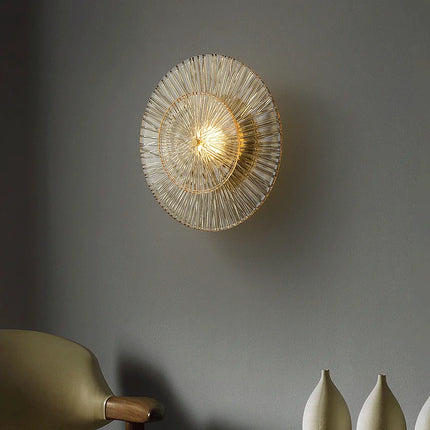 Applique murale dorée en verre strié dans un séjour avec fauteuil et vases en céramique