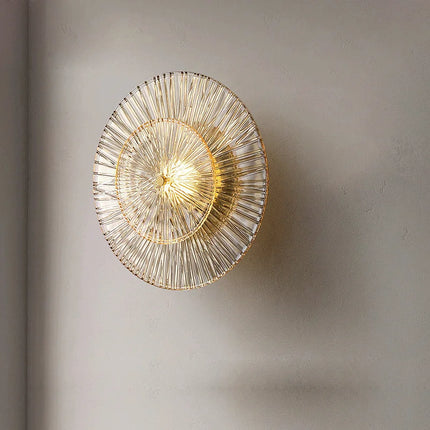Vue de face de l'applique en verre strié doré, deux disques rayonnants sur un mur beige