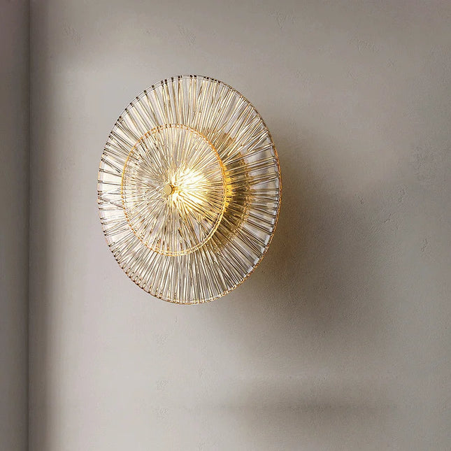 Vue de face de l'applique en verre strié doré, deux disques rayonnants sur un mur beige