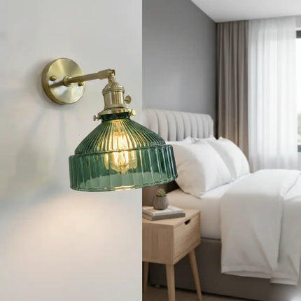 Applique en verre strié vert et laiton allumée en tête de lit dans une chambre nordique