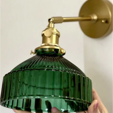 Gros plan sur l'abat-jour en verre vert aux cannelures verticales et sa monture en laiton
