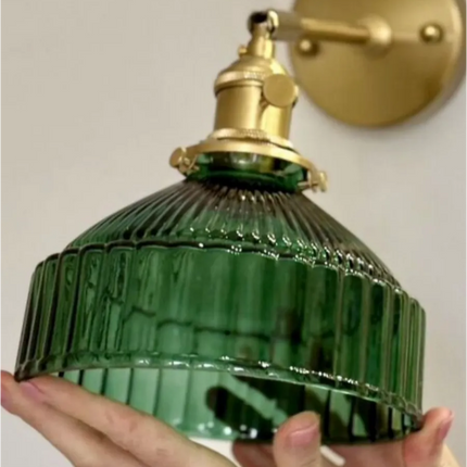 Détail du bras orientable en laiton doré et du verre strié vert profond de l'applique murale