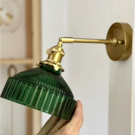 Détail de la douille en laiton doré et de l'abat-jour en verre vert strié de l'applique tenue en main