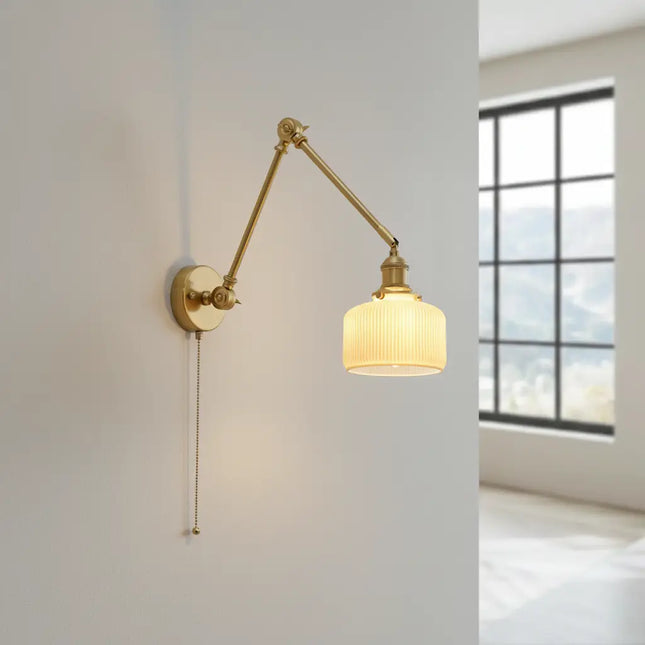 Applique en laiton avec abat-jour céramique allumé diffusant une lumière douce sur un mur beige