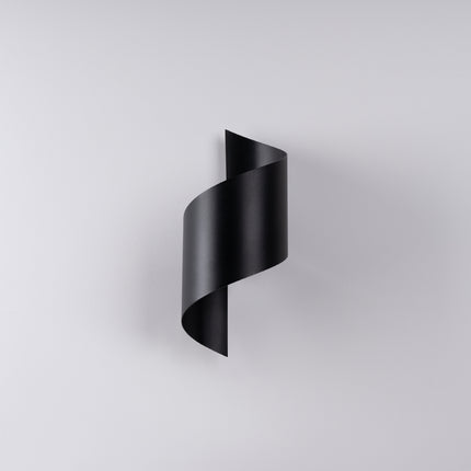 Applique Vortex acier noir allumée sur un mur clair, lumière diffusée en haut et en bas