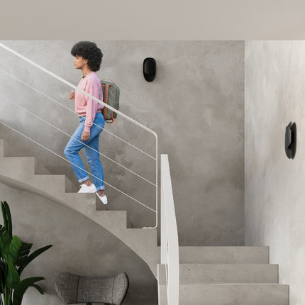 Applique Vortex noire allumée dans une cage d'escalier, avec une personne descendant les marches