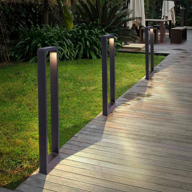 Bornes LED d'extérieur en aluminium anthracite alignées le long d'une allée en bois au jardin