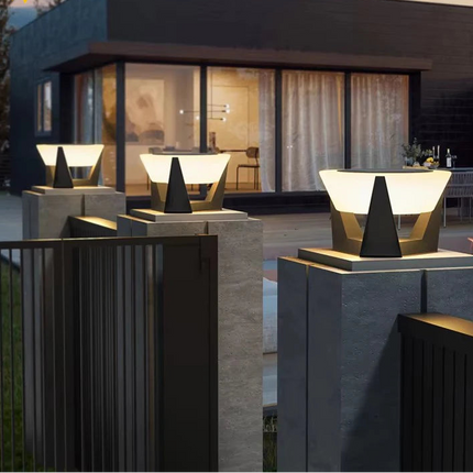 Trois bornes solaires posées sur des piliers devant une maison contemporaine de nuit