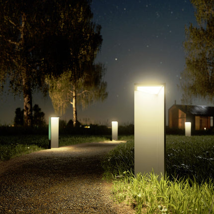 Alignement de bornes solaires Nusolar éclairant une allée de jardin la nuit, ambiance chaleureuse