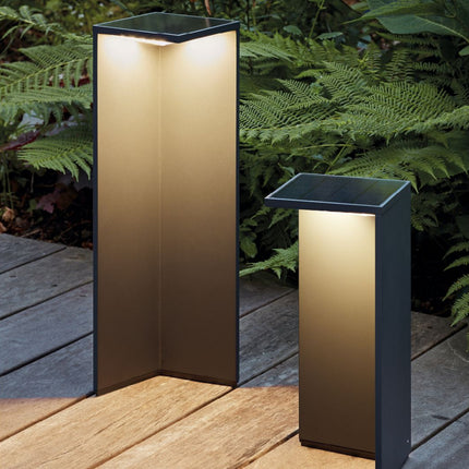 Bornes solaires Nusolar anthracite allumées sur une terrasse en bois, lumière chaude diffusée le long de la structure