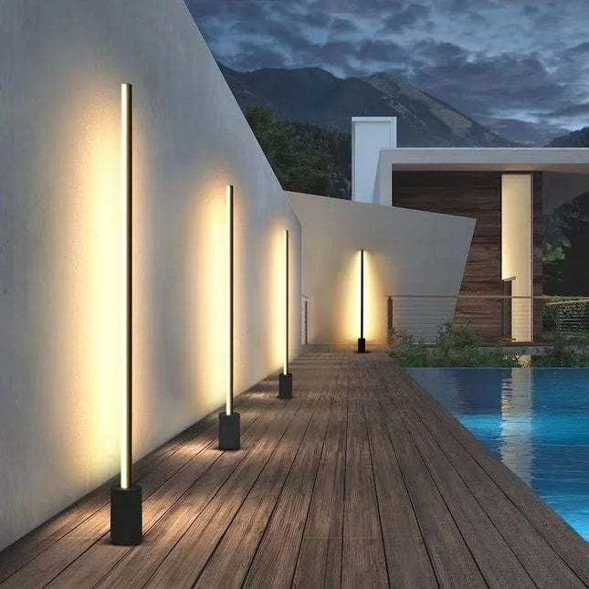 Bornes extérieures LED noires alignées le long d'une terrasse au bord d'une piscine