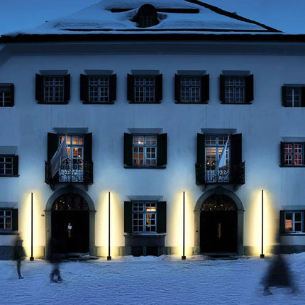 Bornes extérieures LED noires eclairant la facade d'un batiment sous la neige
