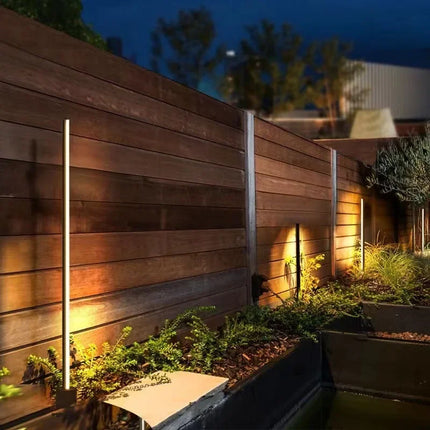 Bornes extérieures LED noires balisant un jardin le long d'une cloture en bois