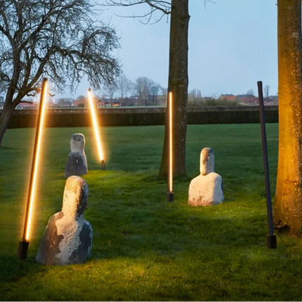 Bornes extérieures LED noires disposees sur une pelouse de jardin au soir