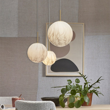 Suspension Carrara globe en verre effet marbre parmi plusieurs luminaires, ambiance salon chaleureux