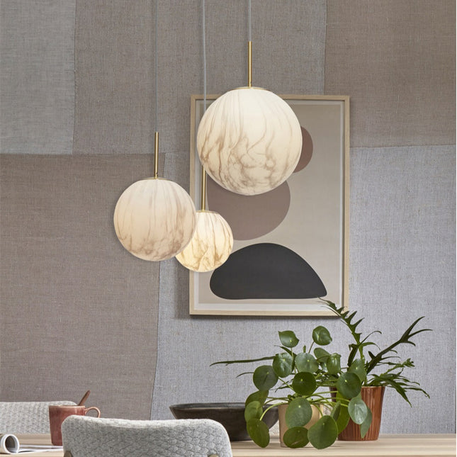 Suspension Carrara globe en verre effet marbre parmi plusieurs luminaires, ambiance salon chaleureux
