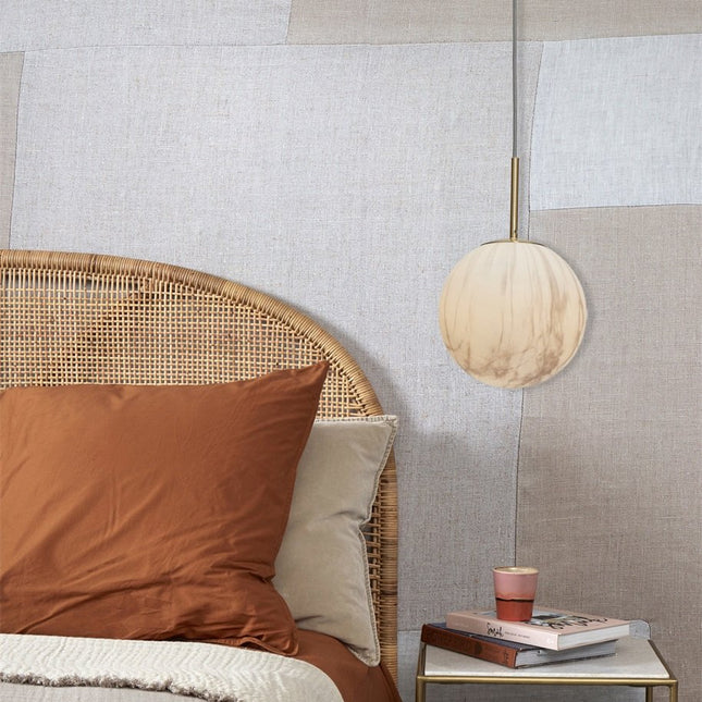 Suspension Carrara globe marbre blanc et doré au-dessus d'une table de chevet en chambre cosy