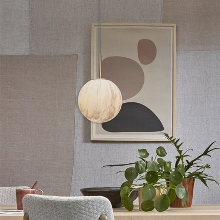 Suspension Carrara globe marbre au-dessus d'une console en bois clair, ambiance salle à manger