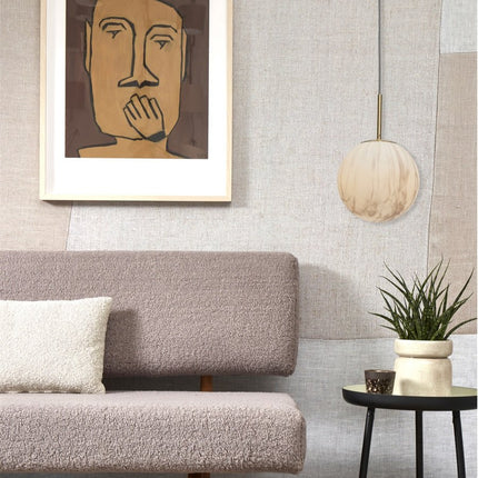 Suspension Carrara globe marbre suspendue près d'un canapé beige et d'une table d'appoint noire