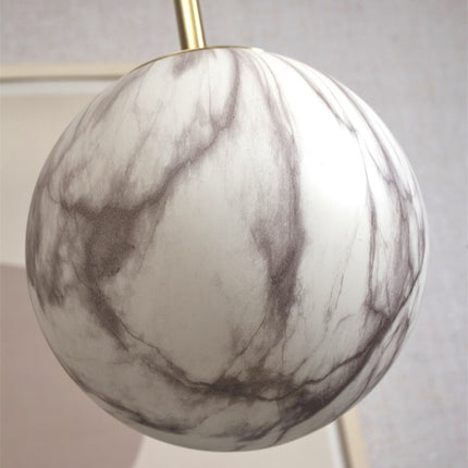 Gros plan sur la texture veinée du globe en verre effet marbre de la suspension Carrara