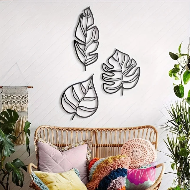 Trio de feuilles murales en métal noir dans un salon bohème avec banquette en rotin et coussins colorés