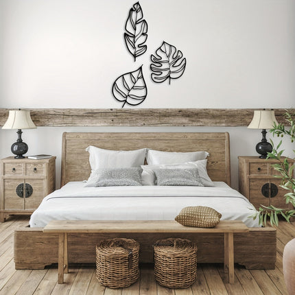 Décoration murale trois feuilles en métal noir au-dessus d'une tête de lit en bois dans une chambre nature