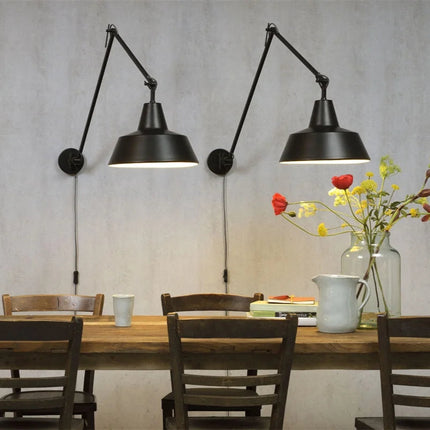 Deux appliques Chicago noires avec câble textile visible, éclairant une table de repas dans un intérieur naturel