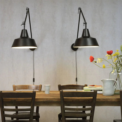 Deux appliques murales Chicago noires en fer suspendues au-dessus d'une table à manger en bois brut