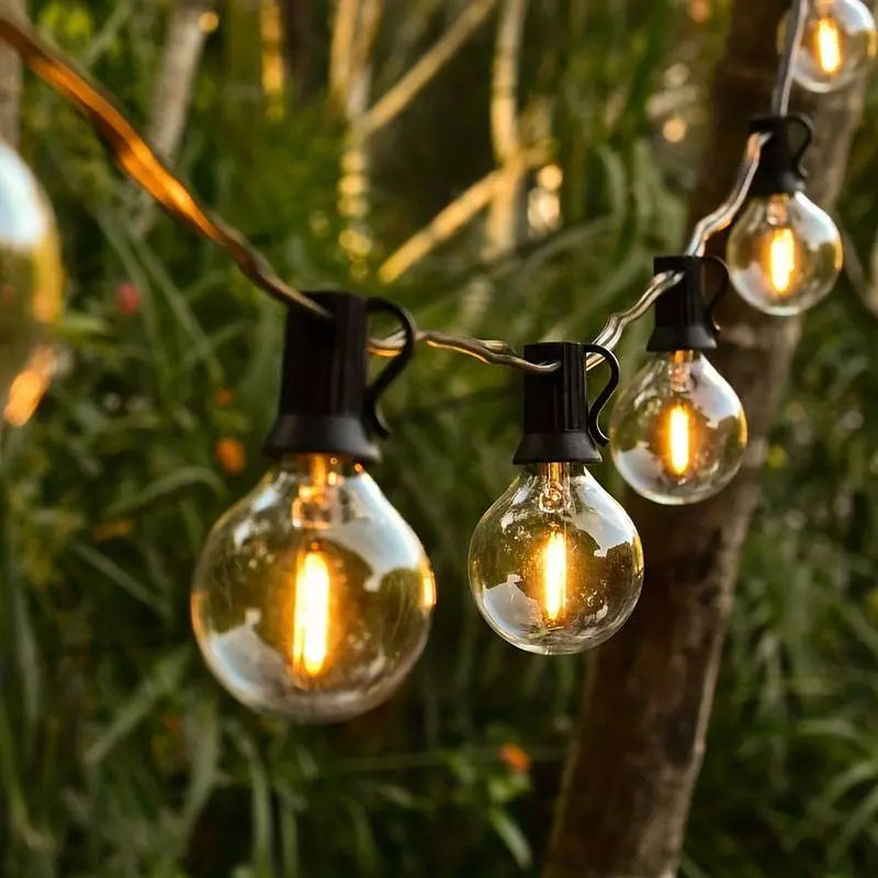 Guirlande Lumineuse Extérieure accrochée entre des arbres dans un jardin.