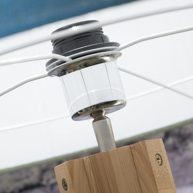 Gros plan sur la douille en métal chromé et le câble textile du lampadaire Annapurna, fixée sur le pied en bambou