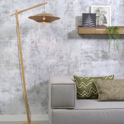 Lampadaire Bali installé dans un salon, sa lumière tamisée traversant l'abat-jour en bambou tressé noir et naturel.