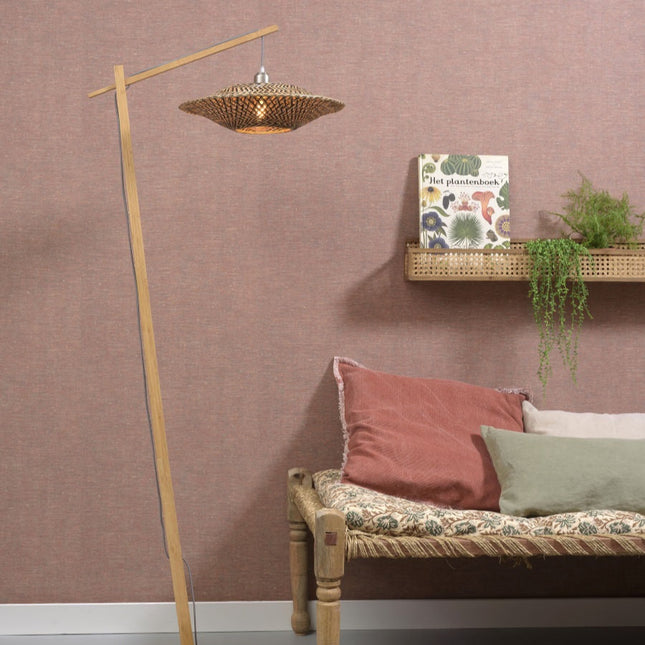 Lampadaire Bali dans un coin lecture chaleureux, structure en bambou clair près d'une banquette et d'une étagère en rotin.
