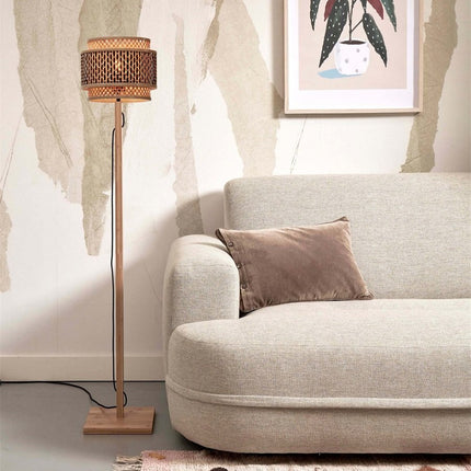 Lampadaire Bhutan bambou naturel et noir installé près d'un canapé beige dans un salon cosy