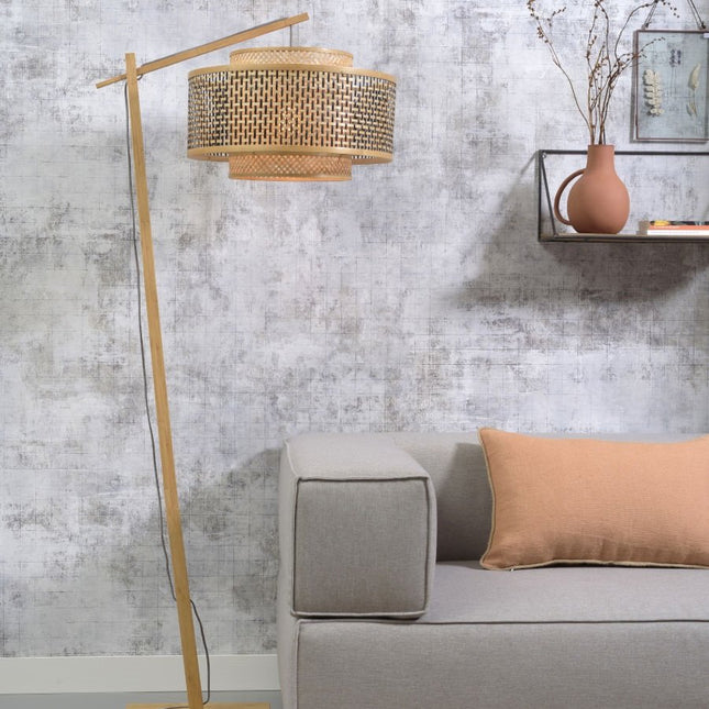 Lampadaire Bhutan en bambou naturel avec abat-jour tressé, dans un salon près d'un canapé gris et d'un coussin terracotta