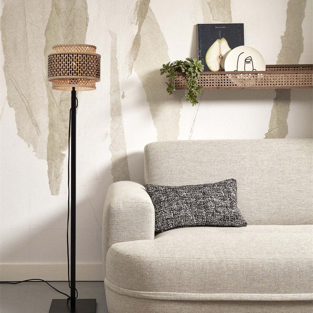 Lampadaire Bhutan en bambou tressé noir et naturel dans un salon, près d'un canapé beige