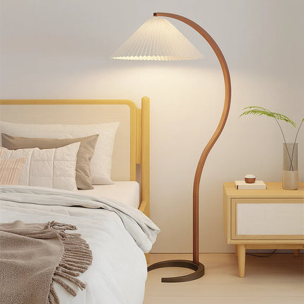 Lampadaire en bois courbé et abat-jour plissé dans une chambre nordique près du lit