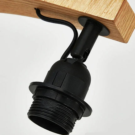 Détail de la douille E27 noire fixée sous le bras en bois du lampadaire nordique
