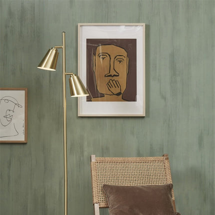 Lampadaire Bremen dore installe pres d'un fauteuil en rotin
