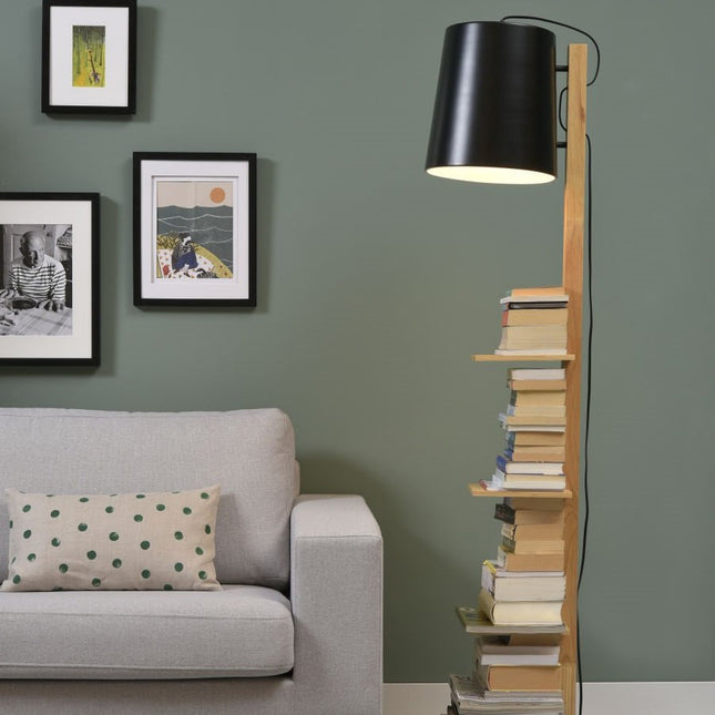 Lampadaire Cambridge dans un salon vert, allumé au-dessus d'une pile de livres rangés sur ses tablettes en bois