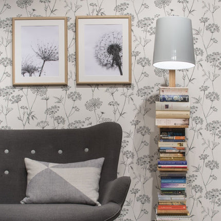 Lampadaire Cambridge bois et fer blanc placé près d'un canapé gris dans un salon lumineux au papier peint fleuri