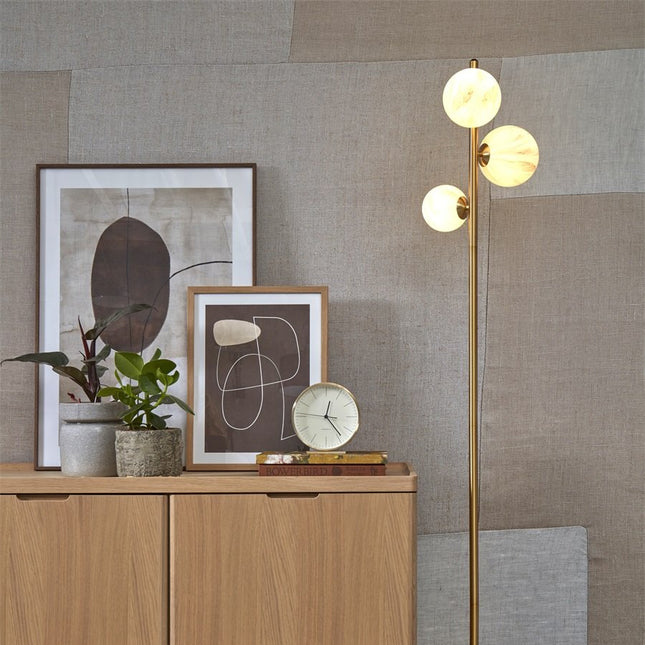 Lampadaire Carrara allumé, lumière douce diffusée par les globes en verre effet marbre près d'un meuble bas